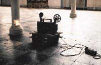 projection of super 8 film on pillar with projector on wooden construction