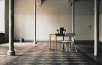 Entrance view with 1 poster searching apartment, cables, super-8 viewer on table with chair, cassette player
